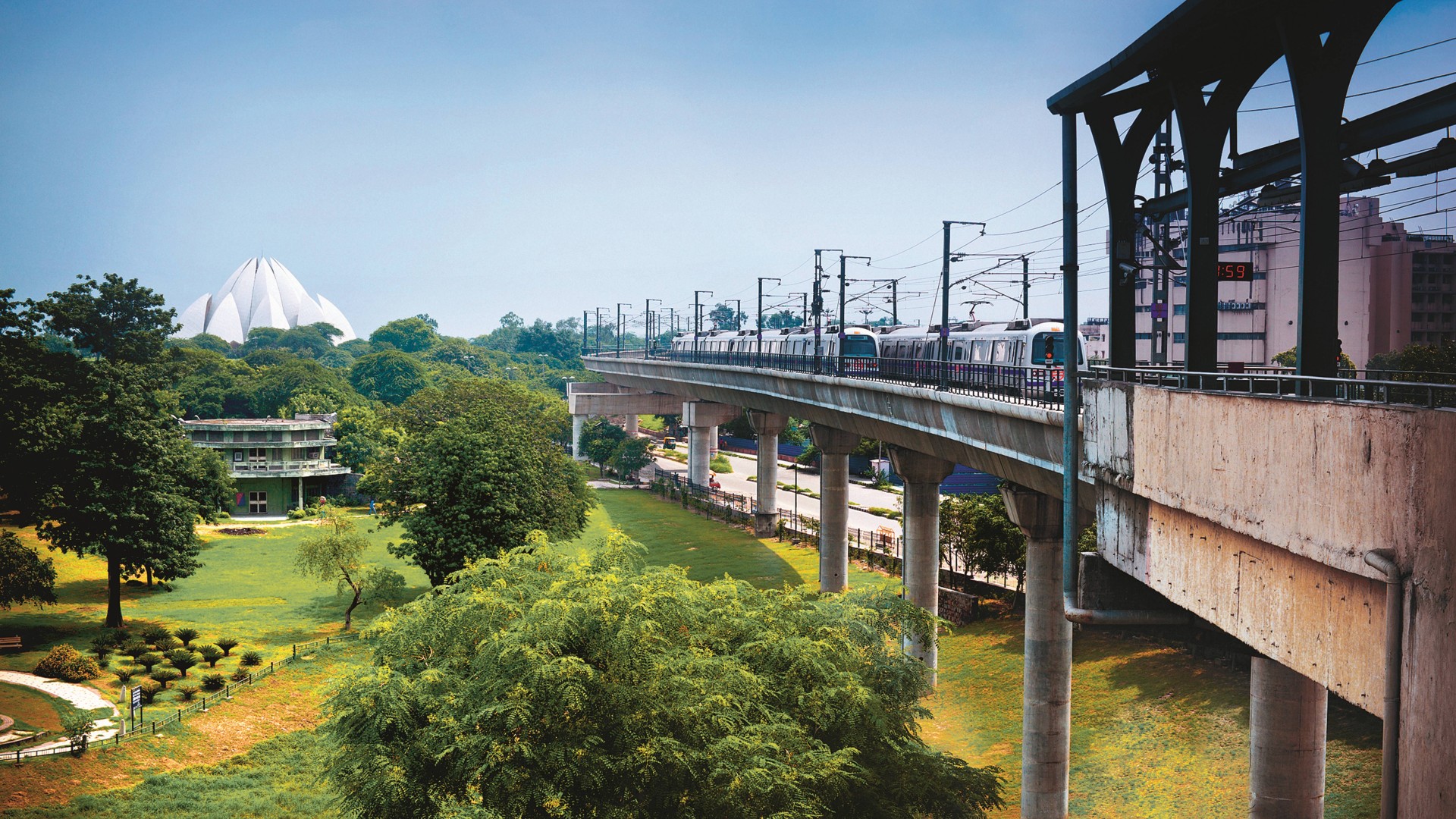 Delhi Metro train on an elevated track near the Lotus Temple in New Delhi, surrounded by green parkland