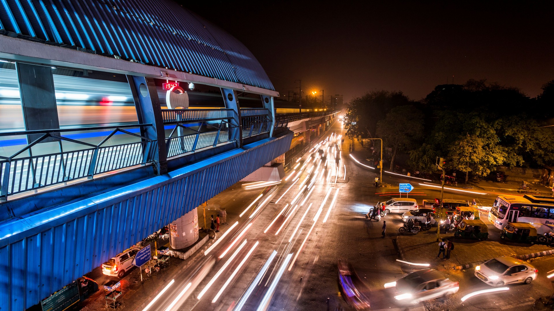 Elevated metro station in New Delhi at night with an illuminated viaduct and heavy road traffic below – showcasing the modern public transport of the Indian capital
