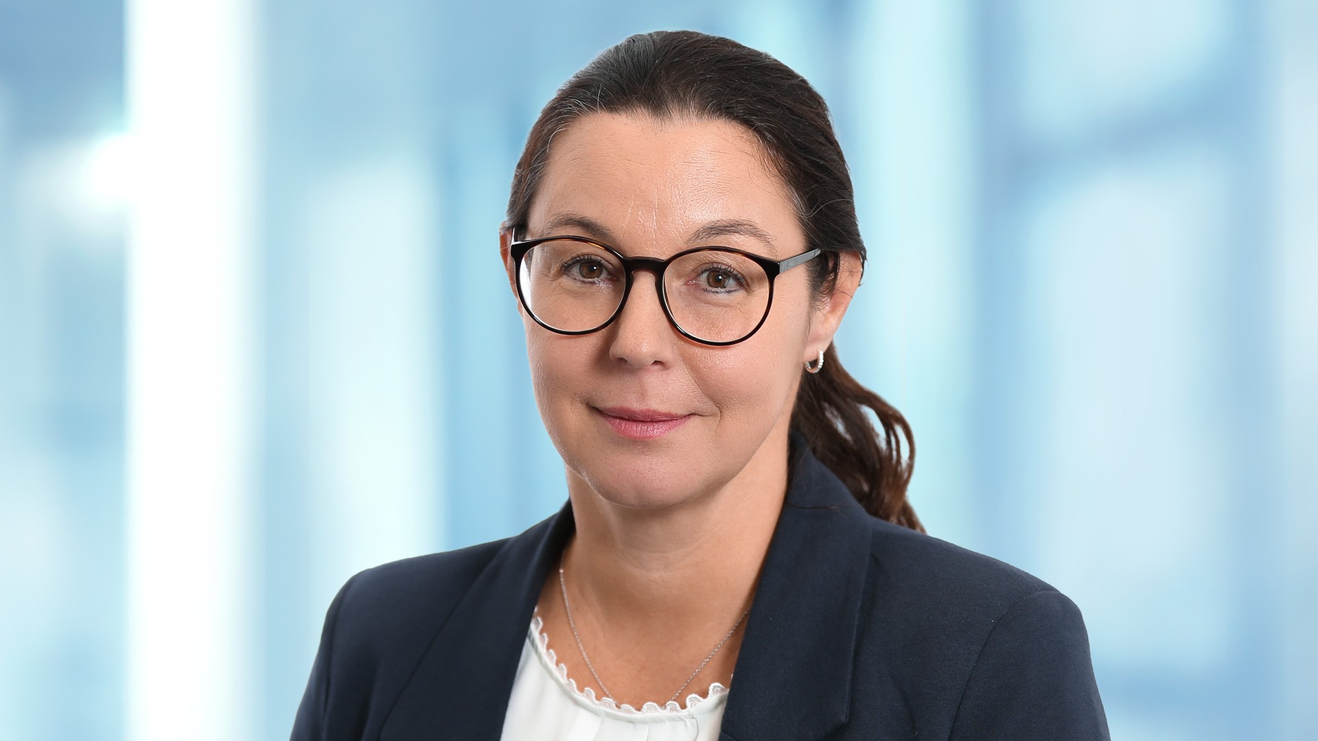 Employee portrait in business attire in front of a modern office background