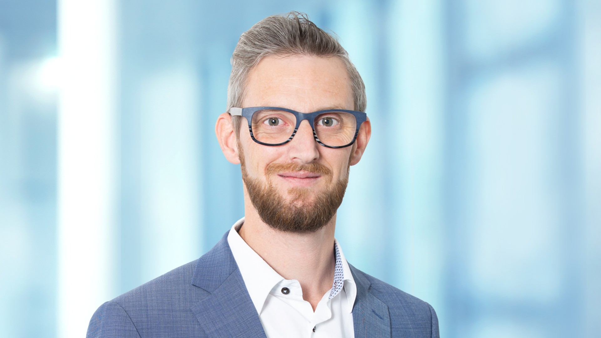 Employee portrait in business attire in front of a modern office background